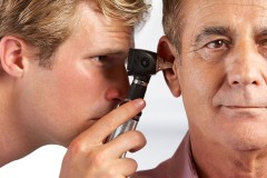 an audiologist examining the ear of a patient